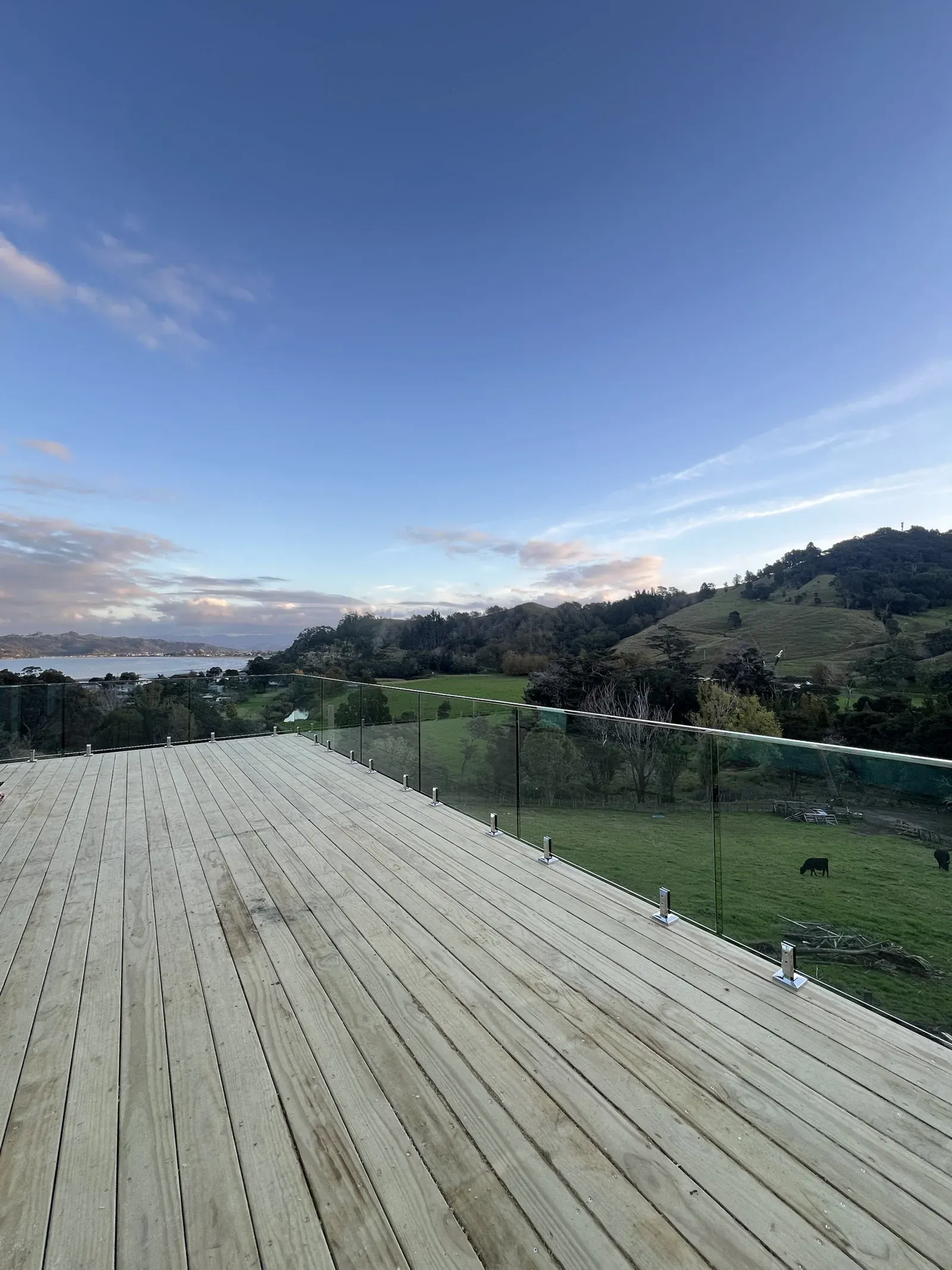 Coromandel: frameless glass deck balustrade overlooking farmland and the harbour, by TK Glass NZ